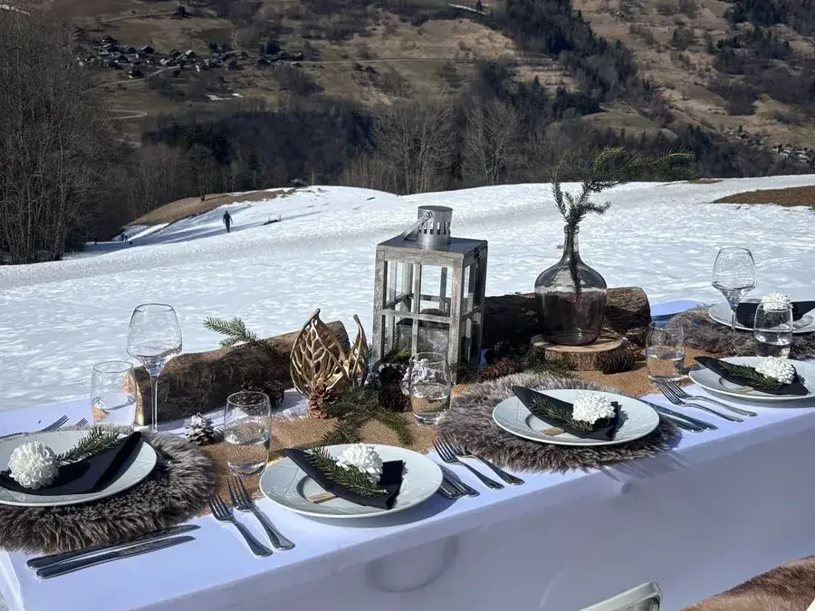 Table dressée dans la neige devant un chalet, chef à domicile pour biens de location