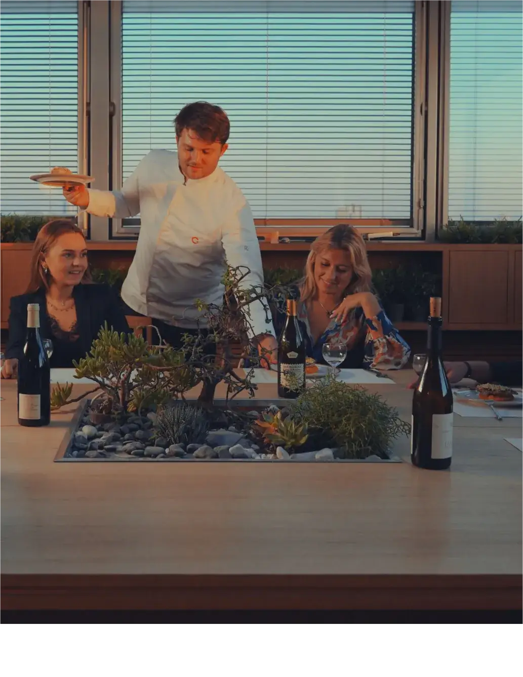Chef à domicile GetChef servant une assiette à deux convives autour d’une table